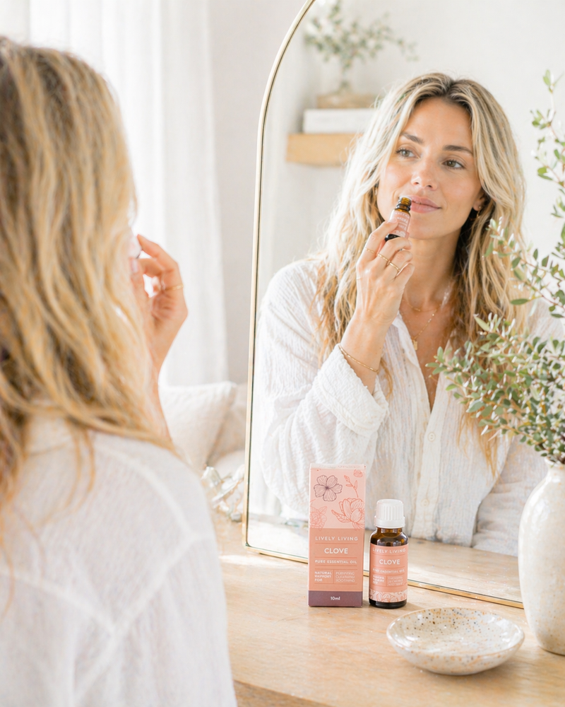 Woman applying makeup in front of a mirror with skincare products on a table.