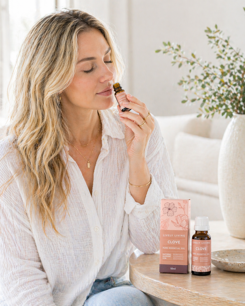 Woman applying essential oil to her hand with a bottle and box on a table.