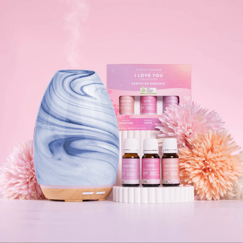 Marble-patterned diffuser with essential oil bottles and packaging on a pink background