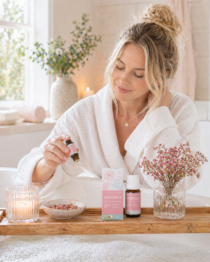 Woman in a bathrobe holding a bottle of essential oil with products on a tray in a spa setting.