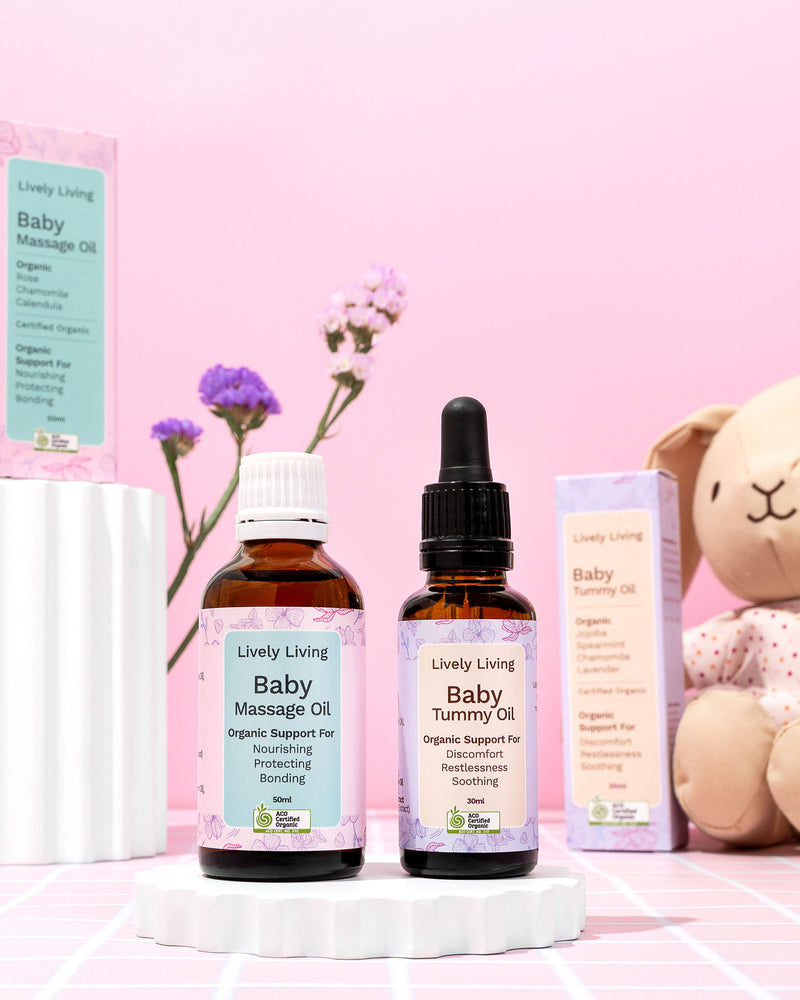 Lively Living baby care products including massage oil, tummy oil, and a dropper bottle on a pink background.