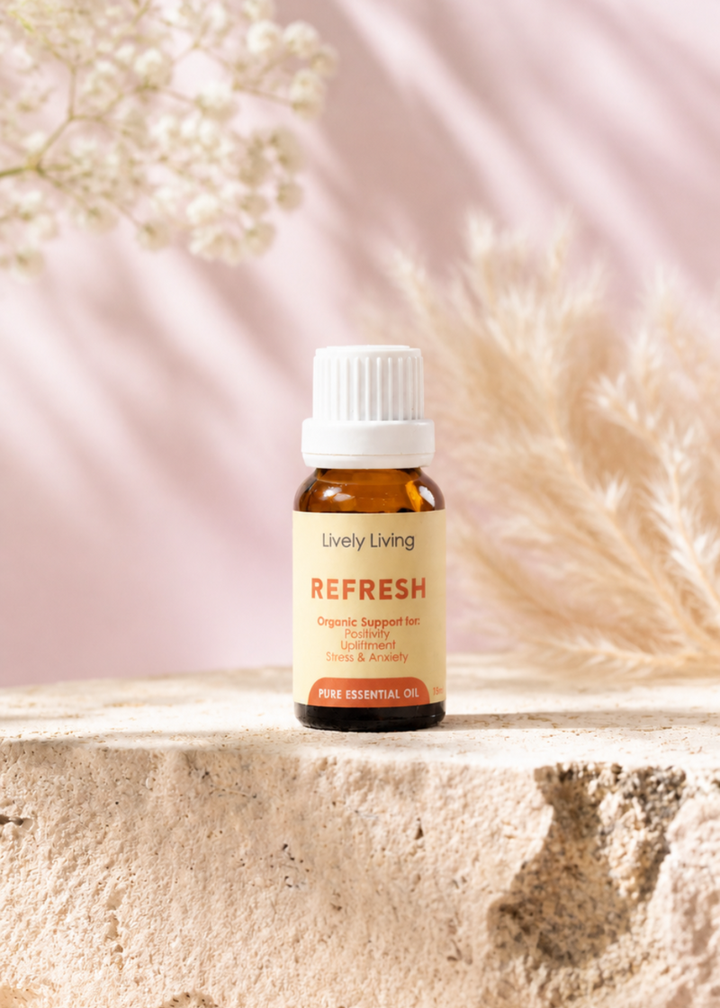 A bottle of Young Living Refresh essential oil on a light surface with a soft pink background and white flowers.