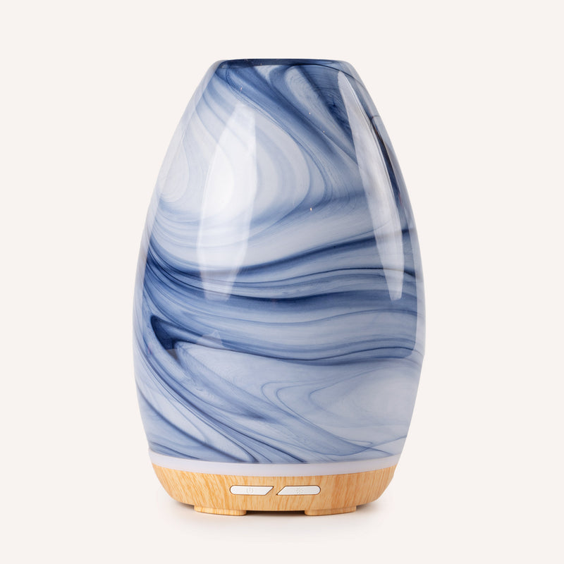 Blue and white marbled diffuser with wooden base on a white background