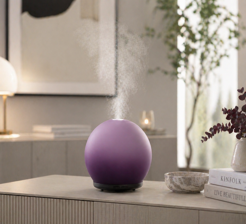 Purple spherical humidifier on a table with steam rising, in a home setting.