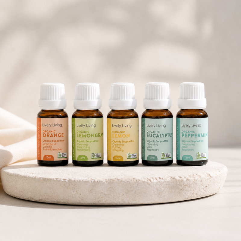 Five bottles of Lively Living essential oils on a stone surface with a neutral background