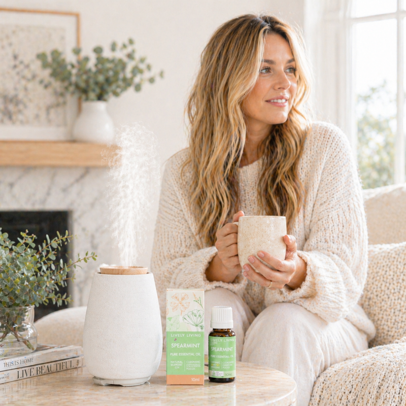 Woman holding a mug in a cozy living room with Spearmint essential oils and a diffuser on a table.