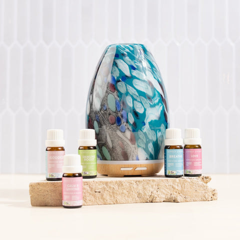 Aromatherapy diffuser with essential oil bottles on a wooden block against a white background