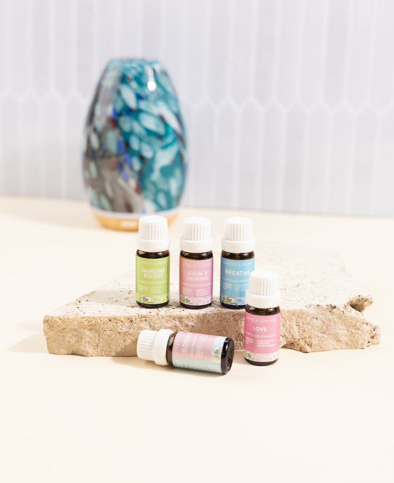 Set of essential oil bottles on a wooden surface with a decorative vase in the background.