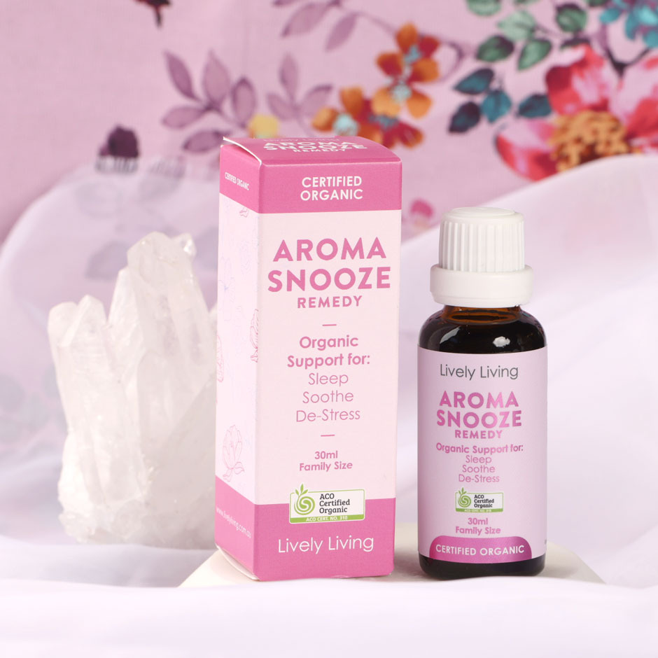 Aroma Snooze Remedy 30ml certified organic bottle and box beside clear quartz against a pink floral backdrop