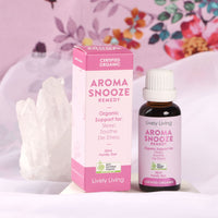 Aroma Snooze Remedy 30ml certified organic bottle and box beside clear quartz against a pink floral backdrop