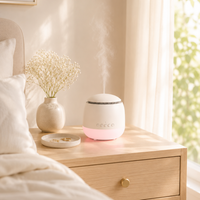 White diffuser on a wooden nightstand next to a vase with dried flowers, in a softly lit bedroom.