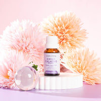 Lively Living "child calming" essential oil bottle sitting on a white rippled plinth surrounded by pink and orange flowers on a pink background
