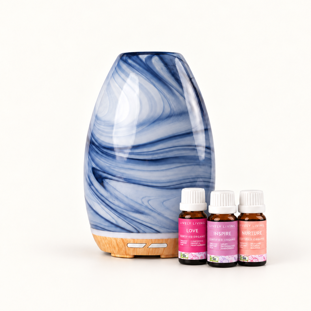 Aroma-Swirl Denim Glass Diffuser in blue and white swirled glass beside the three oils of the I Love You trio on a cream background