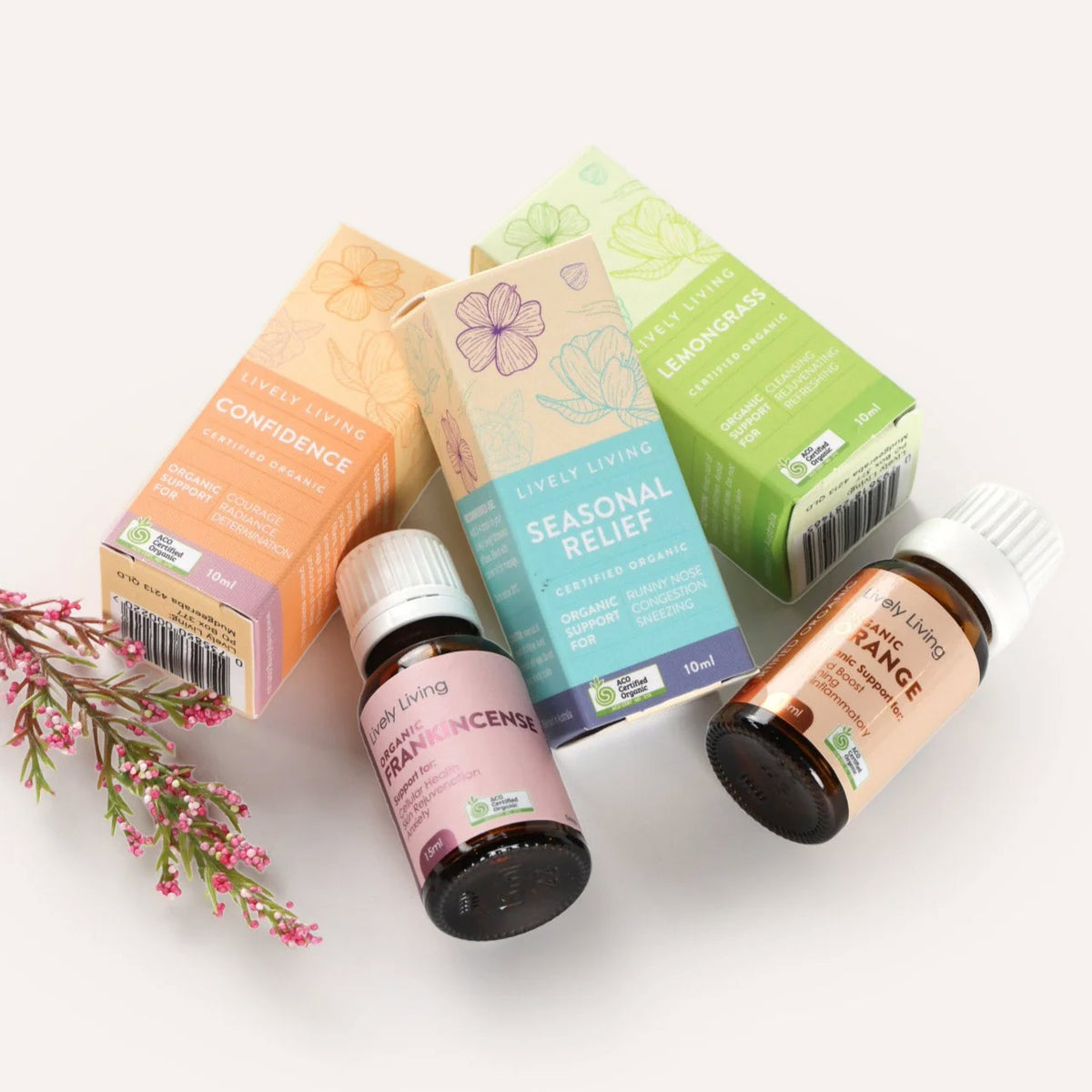 Two essential oil bottles and their packaging on a white background with flowers.