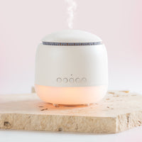 White essential oil diffuser on a wooden surface with a soft light inside