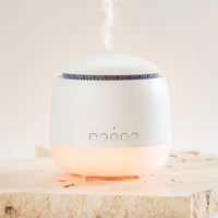 White diffuser emitting a soft glow on a light wooden surface