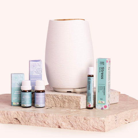 Essential oil diffuser and bottles on a stone surface with a white background