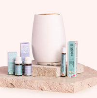 Essential oil diffuser and bottles on a stone surface with a white background