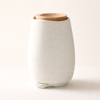 White ceramic vase with a wooden lid on a light beige background