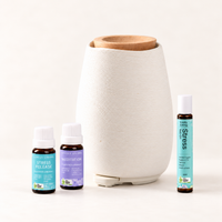 White ceramic Aroma-Fern diffuser with a bamboo lid beside Lively Living Stress Release and Meditation oils and a Stress roll-on, from the Aroma-Fern Calm Starter Set