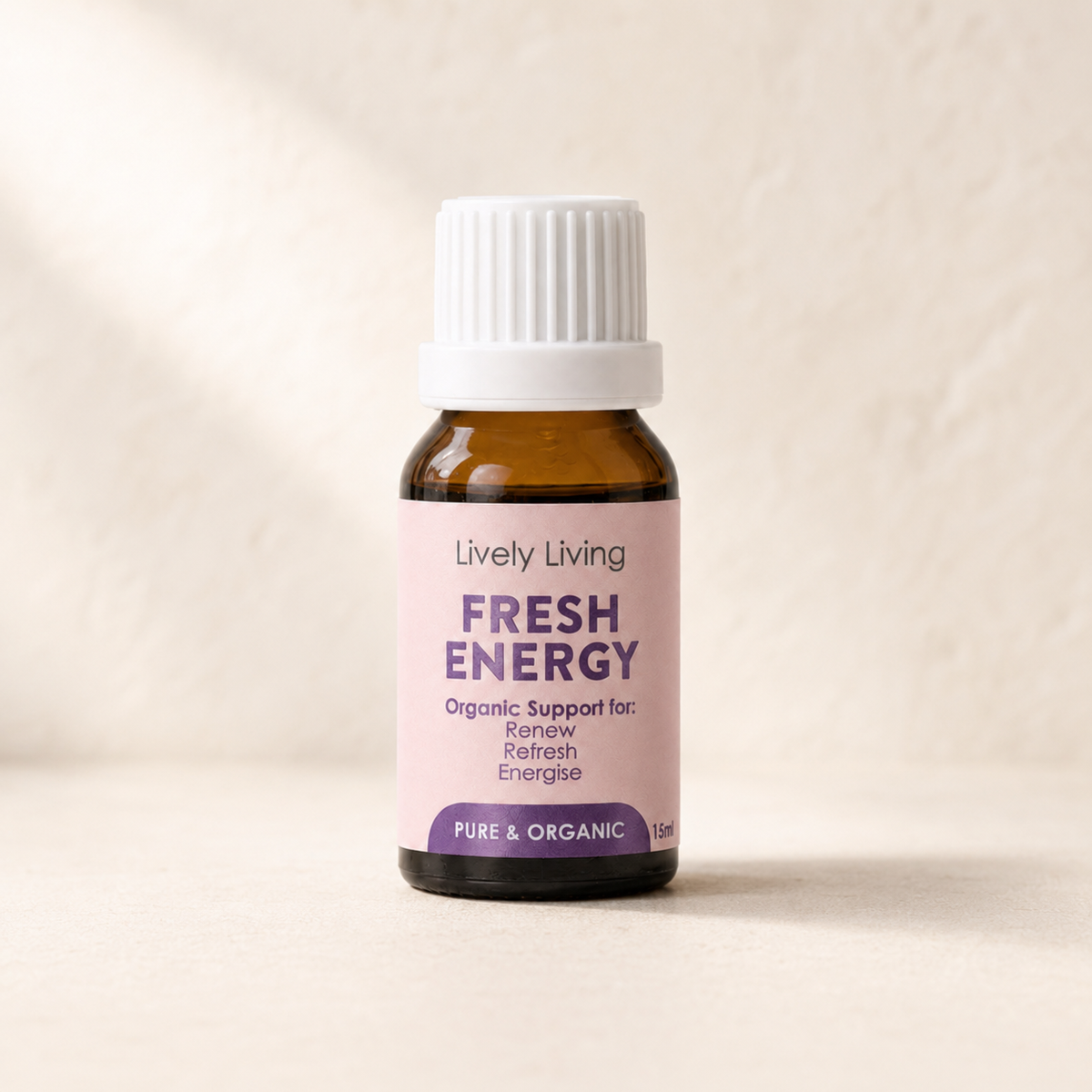 A small amber glass bottle with a white ribbed cap and a pale pink label reading 'Lively Living Fresh Energy' on a warm beige background.