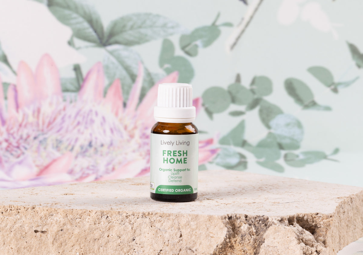 Fresh Home Organic Oil by Lively Living. Sitting on a sand stone block. With a floral background