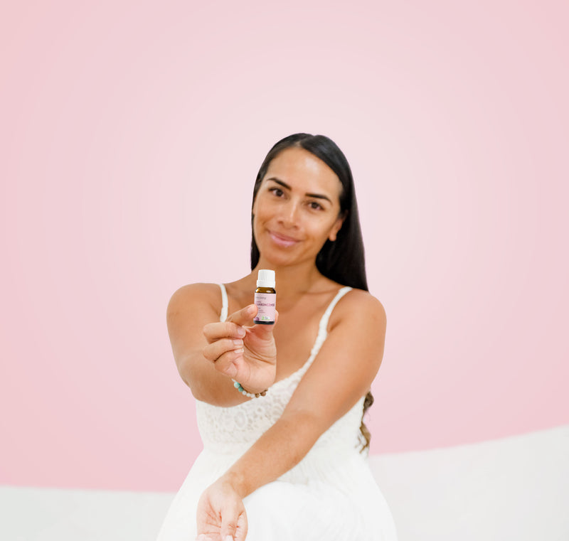 Woman holding Lively Living Frankincense oil  against a pink background