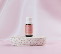 Lively Living essential Grapefruit oil is sitting on  terrazzo platform wit a light pink background. 