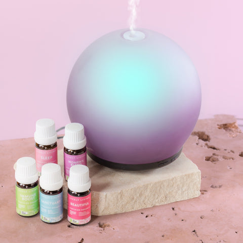 Gradient-colored diffuser with essential oil bottles on a pink background