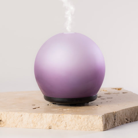 Purple spherical diffuser on a light wooden surface with a white background