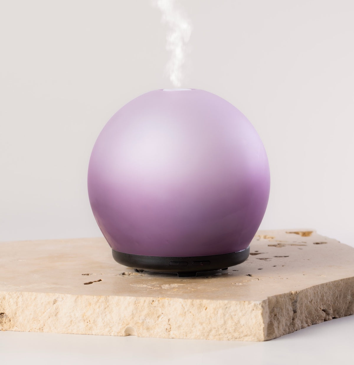 Purple spherical diffuser on a light wooden surface with a white background