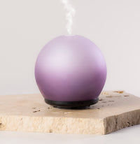 Purple spherical diffuser on a light wooden surface with a white background