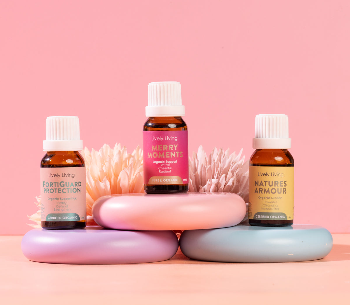 Three bottles of Uplive Living essential oils on a pink background