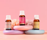 Three bottles of Uplive Living essential oils on a pink background