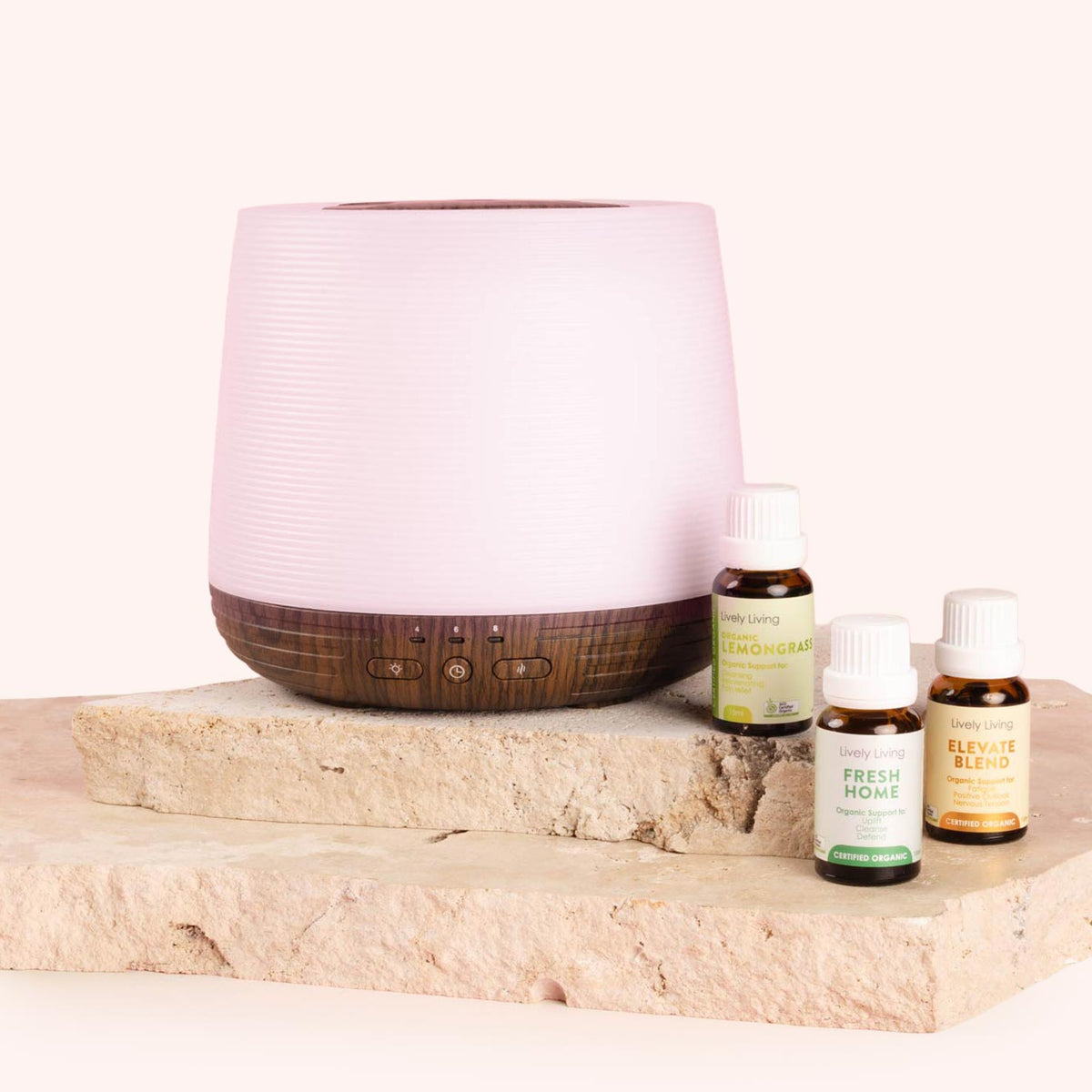 Pink and wooden diffuser with essential oil bottles on a stone surface