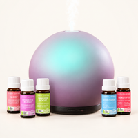 Aroma-Halo Glass Diffuser in iridescent mauve with an aqua glow, releasing mist behind five Lively Living certified organic oils: Sleep, Women's Blend, Immune Boost, Sanctuary and Beautiful