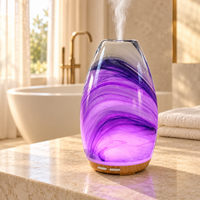 Aroma-Swirl Glass Diffuser glowing purple and releasing mist on a limestone vanity in a sunlit bathroom with a freestanding bath