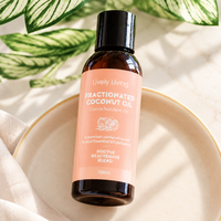 Lively Living Fractionated Coconut Oil in an amber bottle with a peach label, resting on a cream plate with striped green leaves and linen