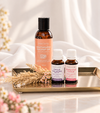 Lively Living Fractionated Coconut Oil with Child Calming and Sensitive Child essential oils on a gold tray, with dried grasses, pink blossom and white drapes