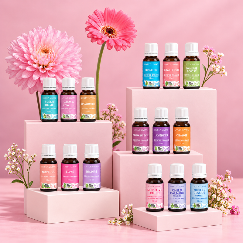 Lively Living essential oil collection displayed on pale pink blocks with pink gerberas and wax flowers