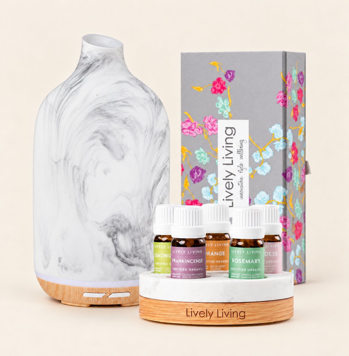 Aroma-Dune Grey Marle diffuser on a wood-look base beside five Lively Living certified organic oils on a round stand and the floral gift box