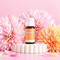 Lively Living Mandarin pure essential oil 10ml bottle on a white pedestal surrounded by pink and peach chrysanthemums