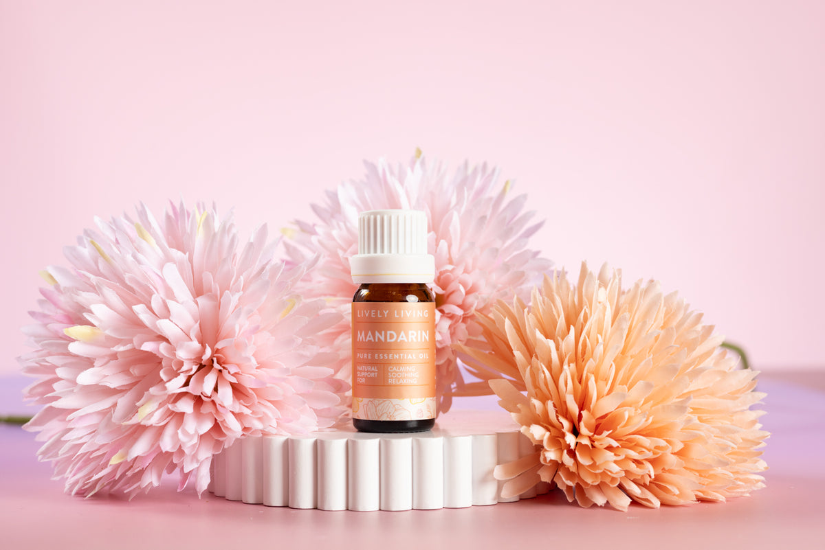 Lively Living Small bottle of mandarin essential oil with pink and peach flowers on a pink background