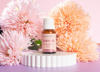 Bottle of Lively Living Nurture product with pink flowers on a pink background
