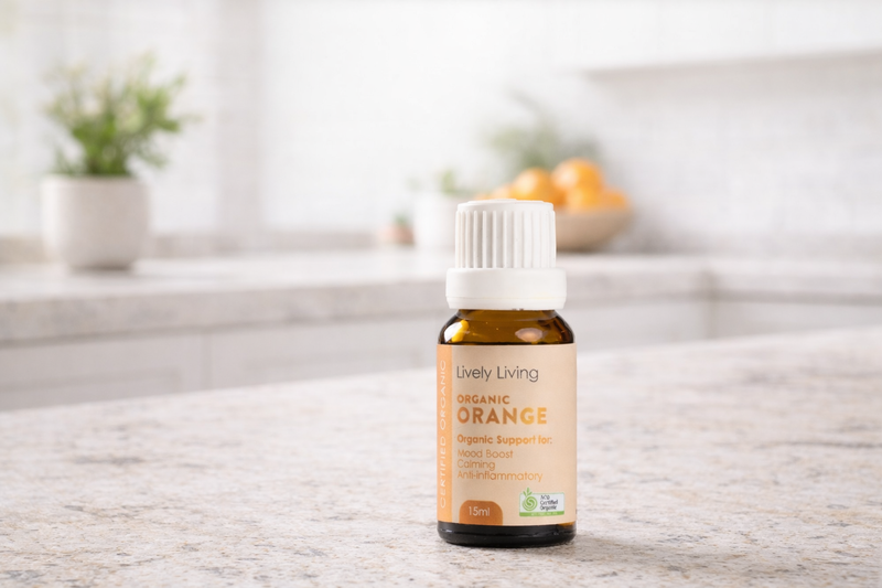 Lively Living Organic Orange essential oil bottle on a wooden surface with a blurred background