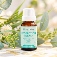 Lively Living Protection Blend certified organic essential oil 15ml bottle with a mint green label, surrounded by eucalyptus leaves and white flowers