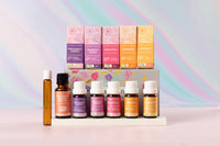Lively Living essential oils, "pregnancy and birth, womens blend, beautiful, orange, harmony" sitting on a white stand with a pink surface and multicolour background