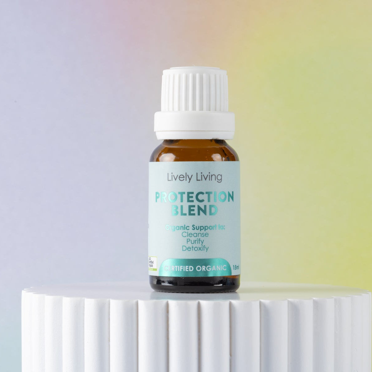 Bottle of Lively Living Protection Blend on a white pedestal with a gradient background