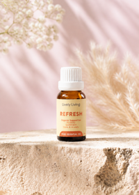 A bottle of Young Living Refresh essential oil on a light surface with a soft pink background and white flowers.