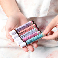 Hands holding five roll-ons: Head Soothe, Focus, Happiness, Snooze and Stress